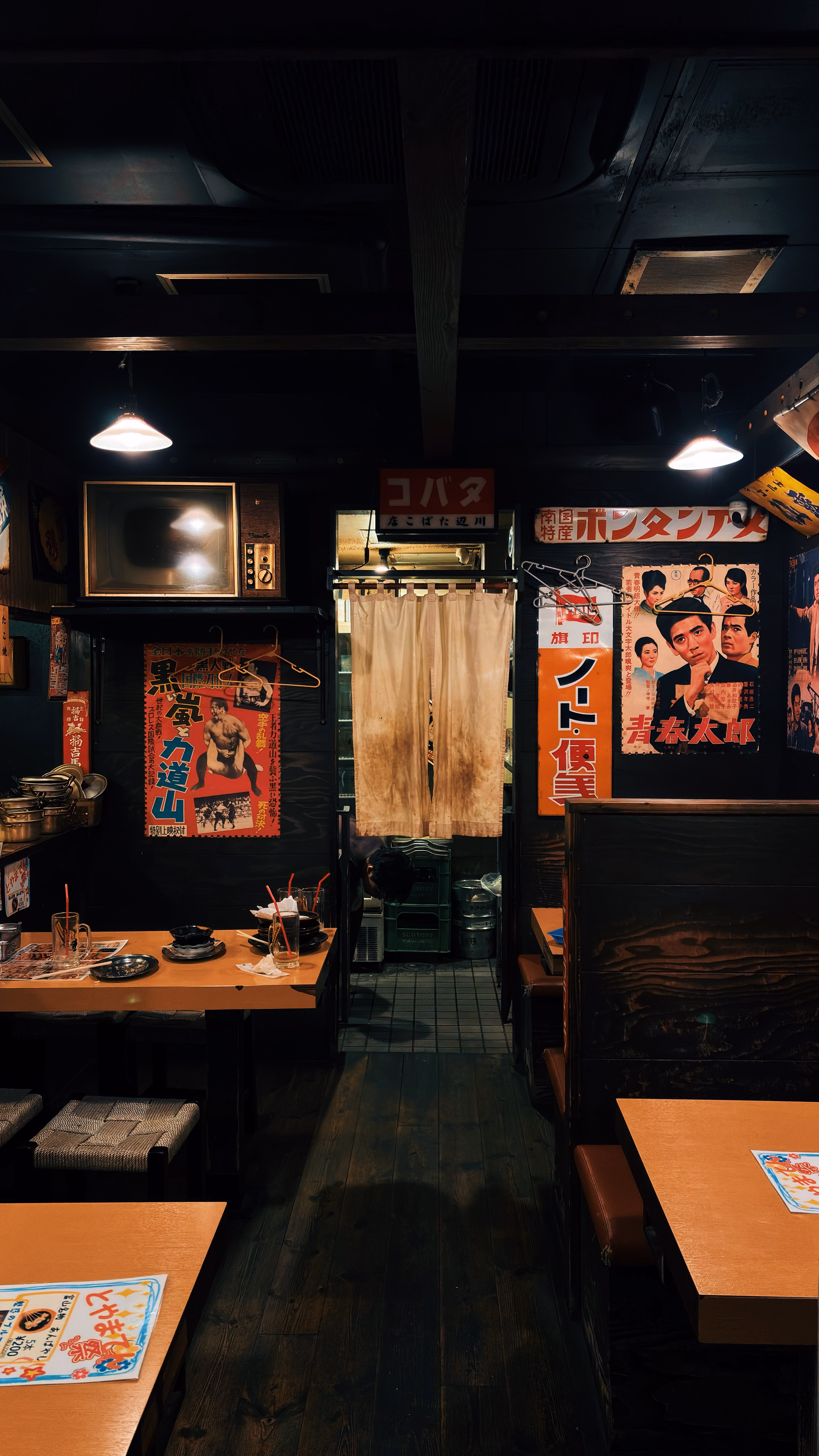 昭和レトロなポスターが並ぶ、暖色の灯りが灯る店内のイメージ写真